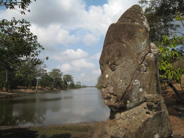 A deva head overlooking the moat round Angkor Thom